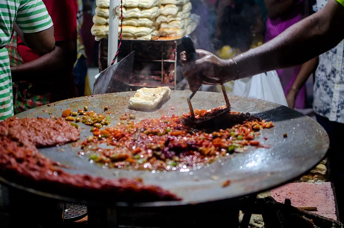Pav bhaji sizzling on a big street-side tawa